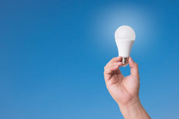 Hand holding LED Bulb with Lighting on blue sky background. Hand holding LED Bulb with Lighting on blue sky background.