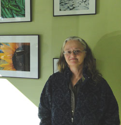 Terry Sprague of North Haven in front of her photography exhibit at NRCM's office in Augusta.