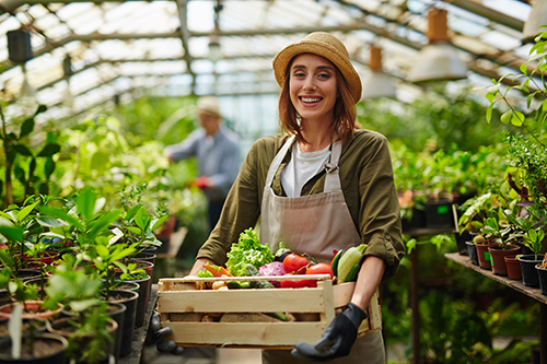 young woman with basket of veggies in greenhouse