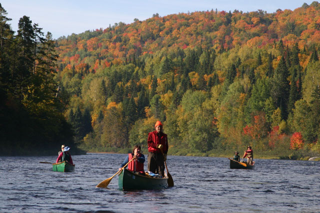 a group of people paddling down river in canoe