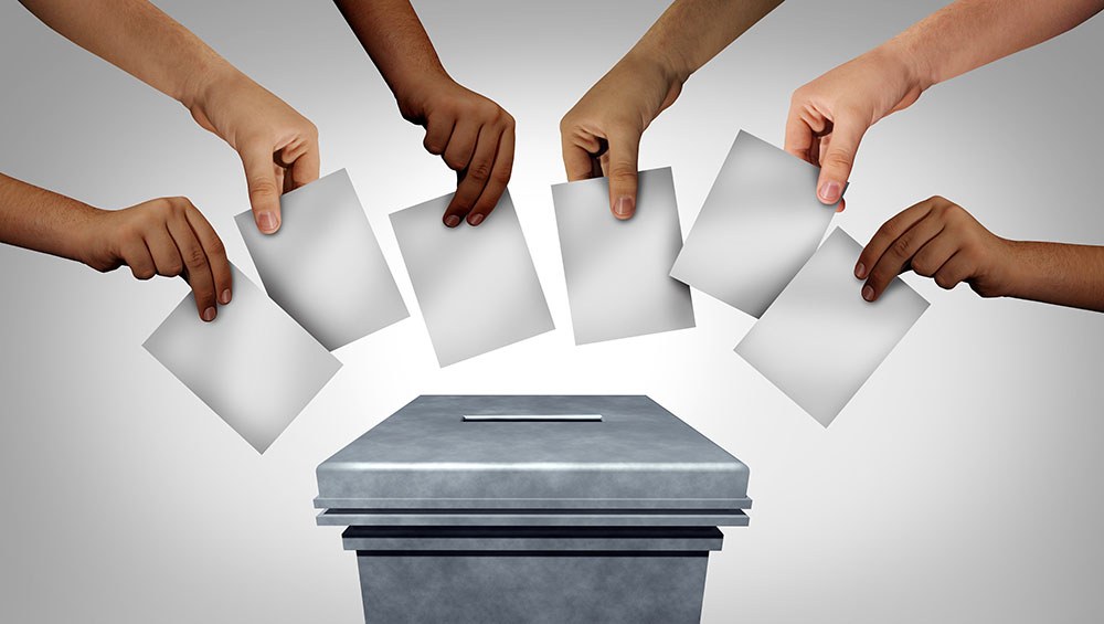 Hands voting with ballot box