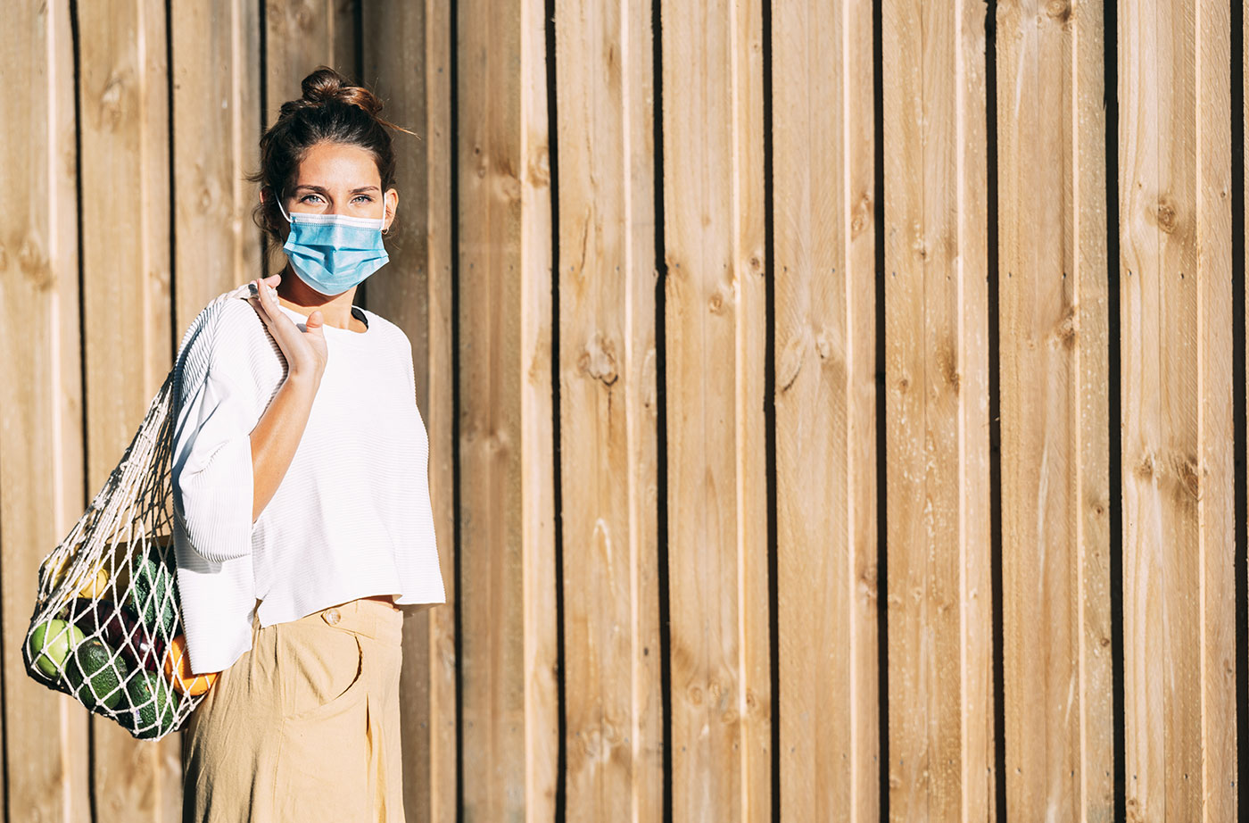 masked woman with reusable bag of groceries