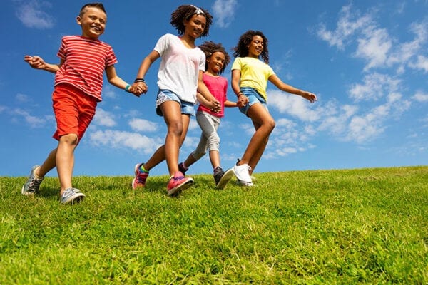 children holding hands running through grass