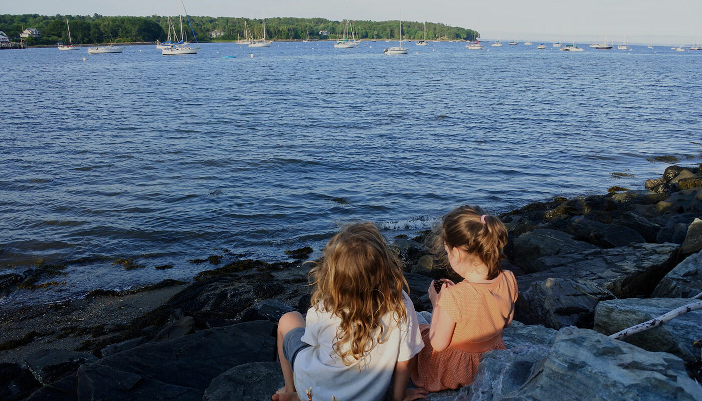 two girls sitting by shore