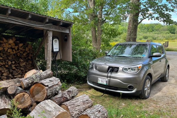 electric car charging by stacked woodpile