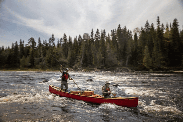 two people in canoe paddling through rapids