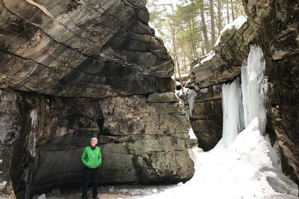 man in front of steep rocks and ice