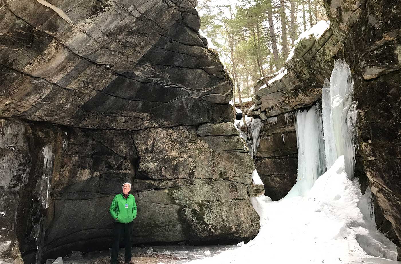 man in front of steep rocks and ice
