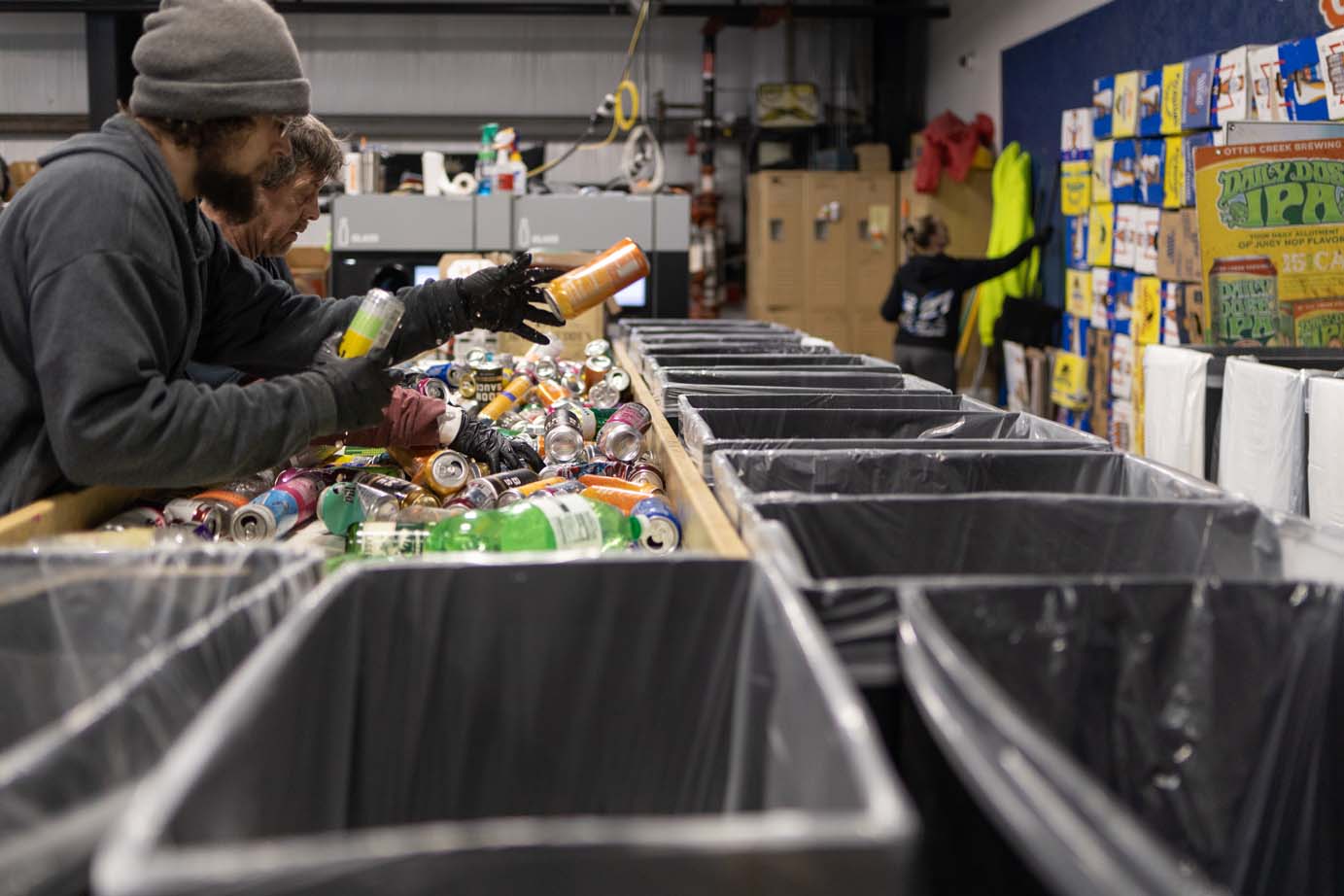 people sorting bottles and cans into cardboard bins