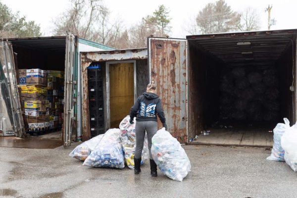 Person mving bags of cans into transportation crates.