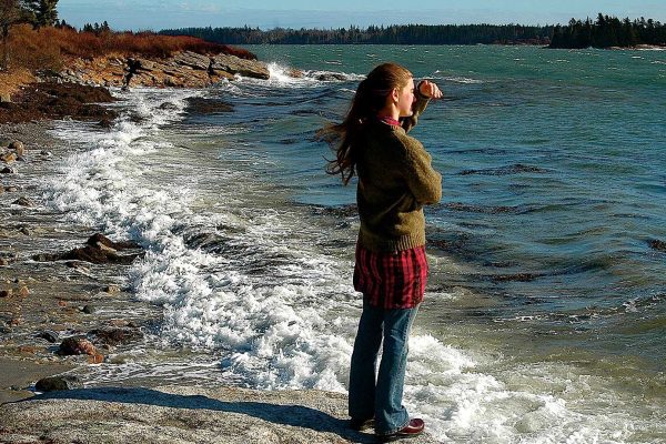 young woman standing in ocean waves looking out at ocean