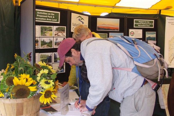 person taking action signing petition at NRCM booth at Common Ground Fair