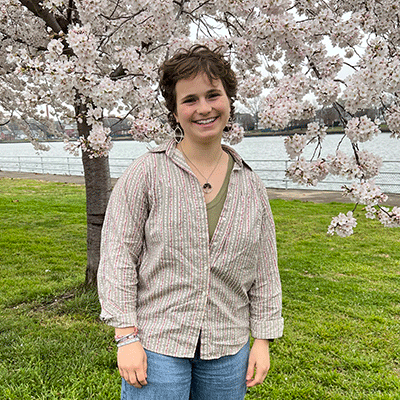 Ella-Allan-Rahill-summer-2023 Ella Allan-Rahill standing in front of blossoming tree