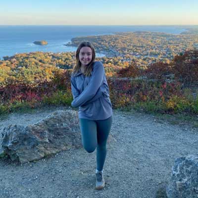 Kaitlyn standing on mountain with coastline behind her