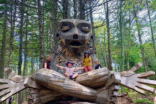 Kids-on-a-troll-at-Coastal-Maine-Botanical-Gardens-Boothbay-Tina-Taylor children sitting on wooden troll in woods