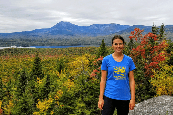 Emmie Theberge wearing NRCM Rising t-shirt while standing on top of Barnard Mountain at KWW