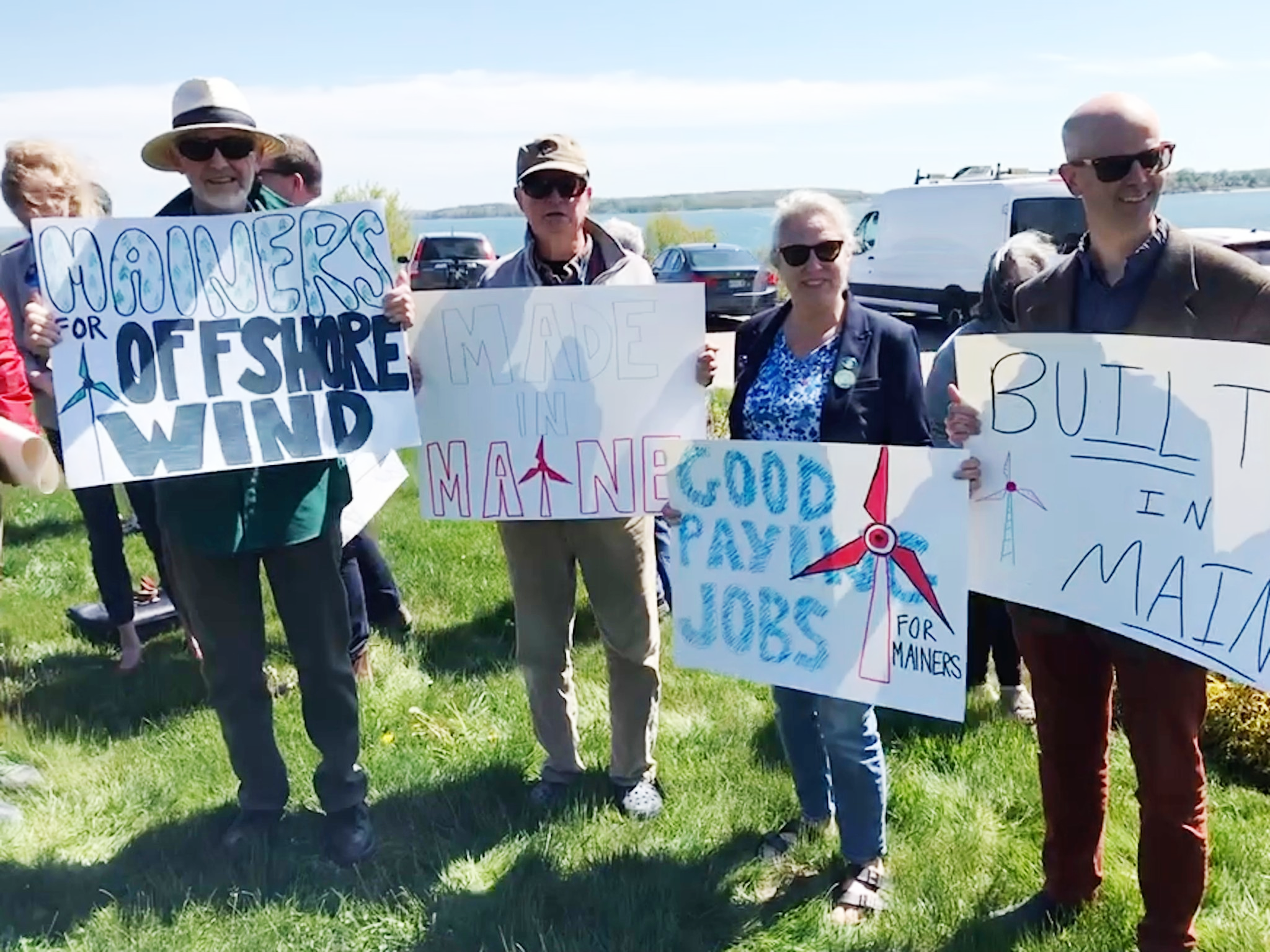 People outside holding signs in support of offshore wind