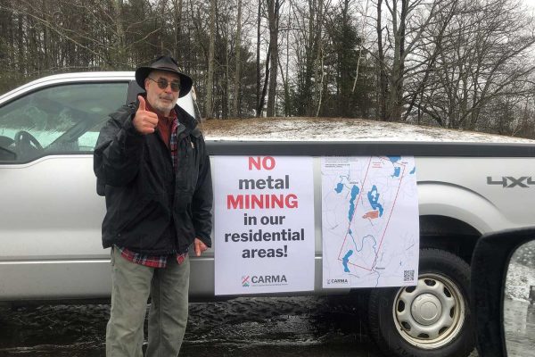 man giving thumbs up standing next to truck with "no mining" signs on it