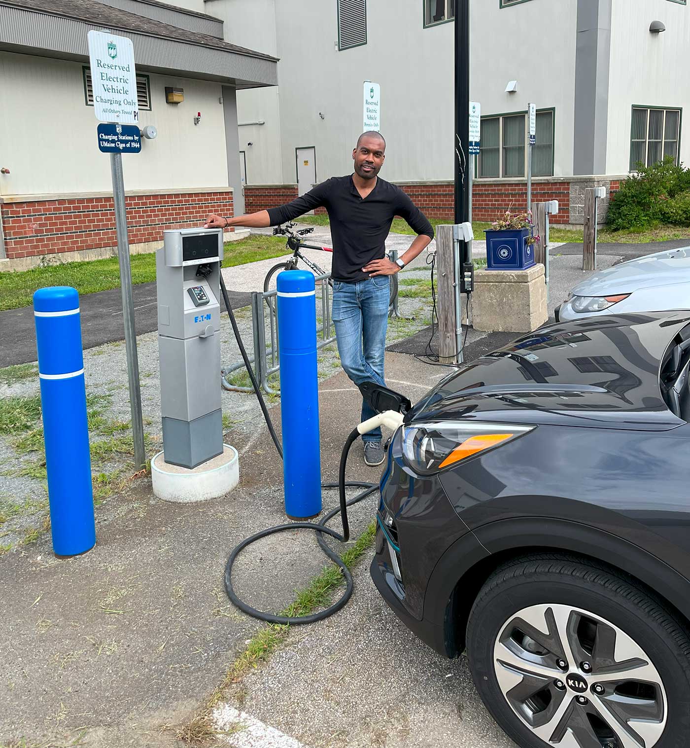 man standing next to electric vehicle charger