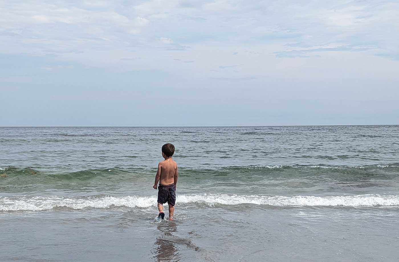Young boy watching ocean waves