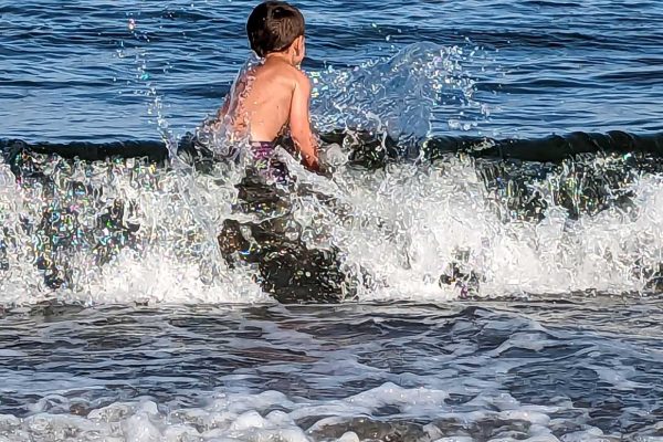 young boy jumping onto ocean wave
