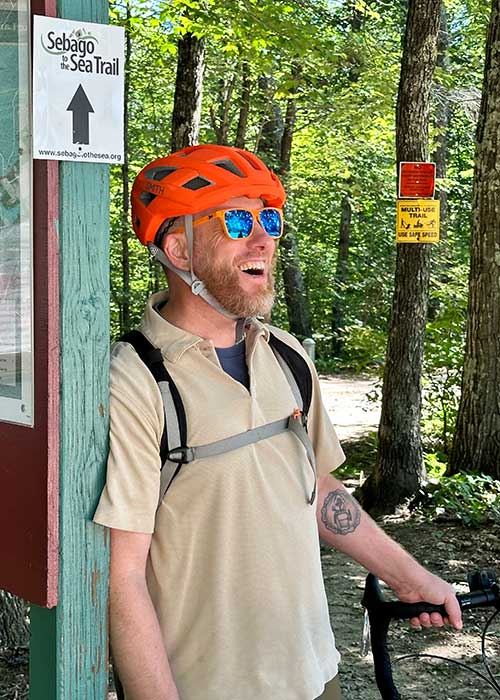 Colin laughing wearing bike helmet on outdoor trail
