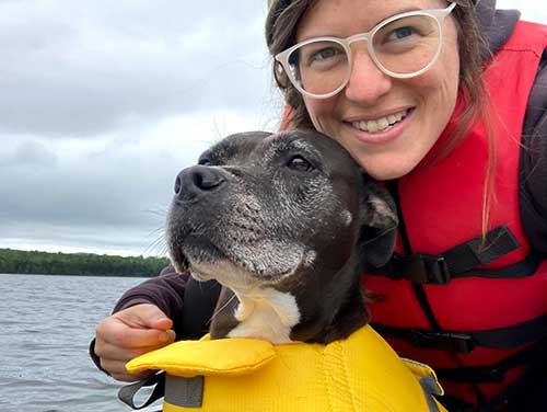 Cp;;een and her dog on water both wearing life vests