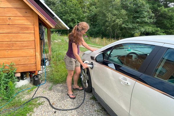 woman charging electric vehicle outside at home