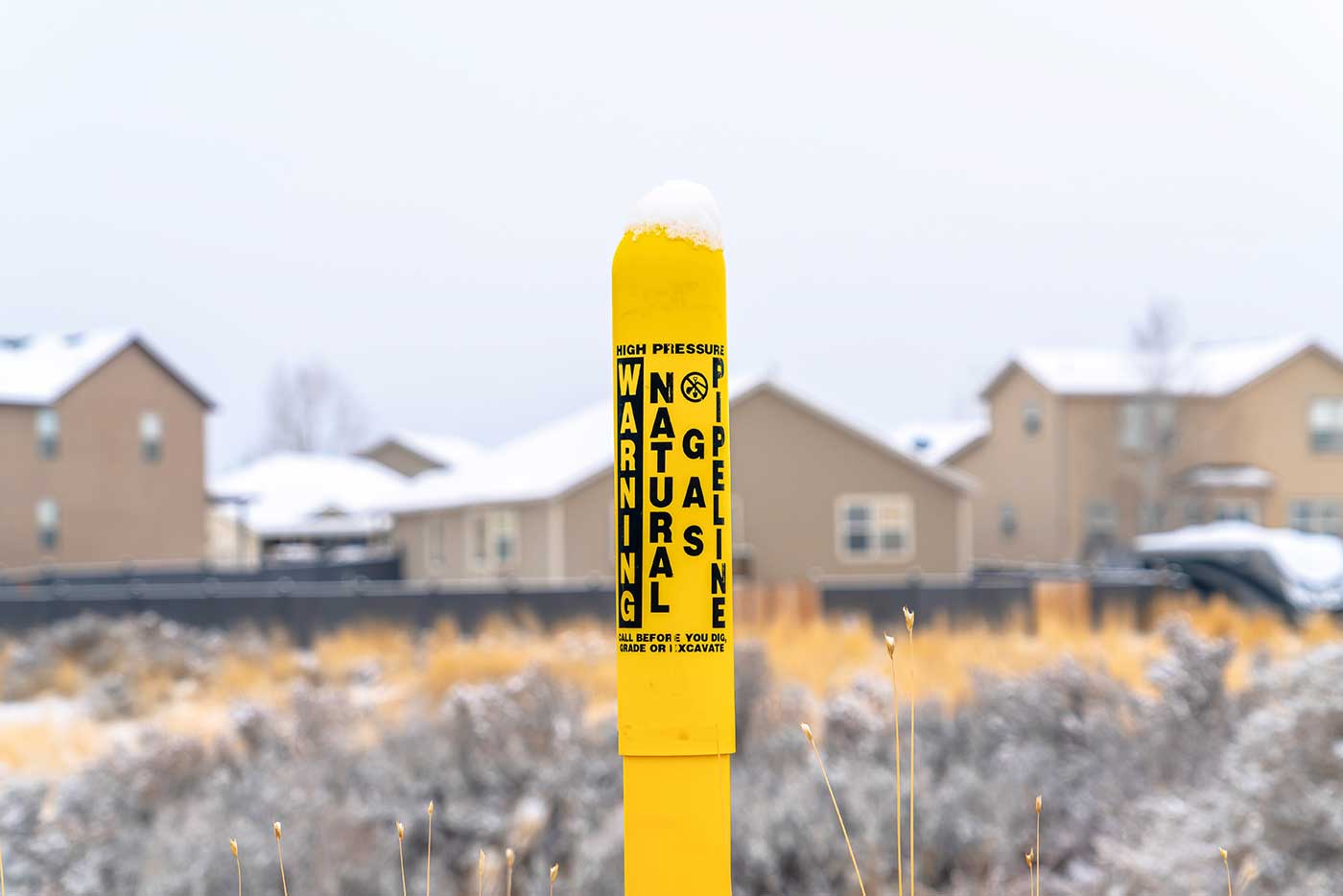 yellow natural gas line marker in ground
