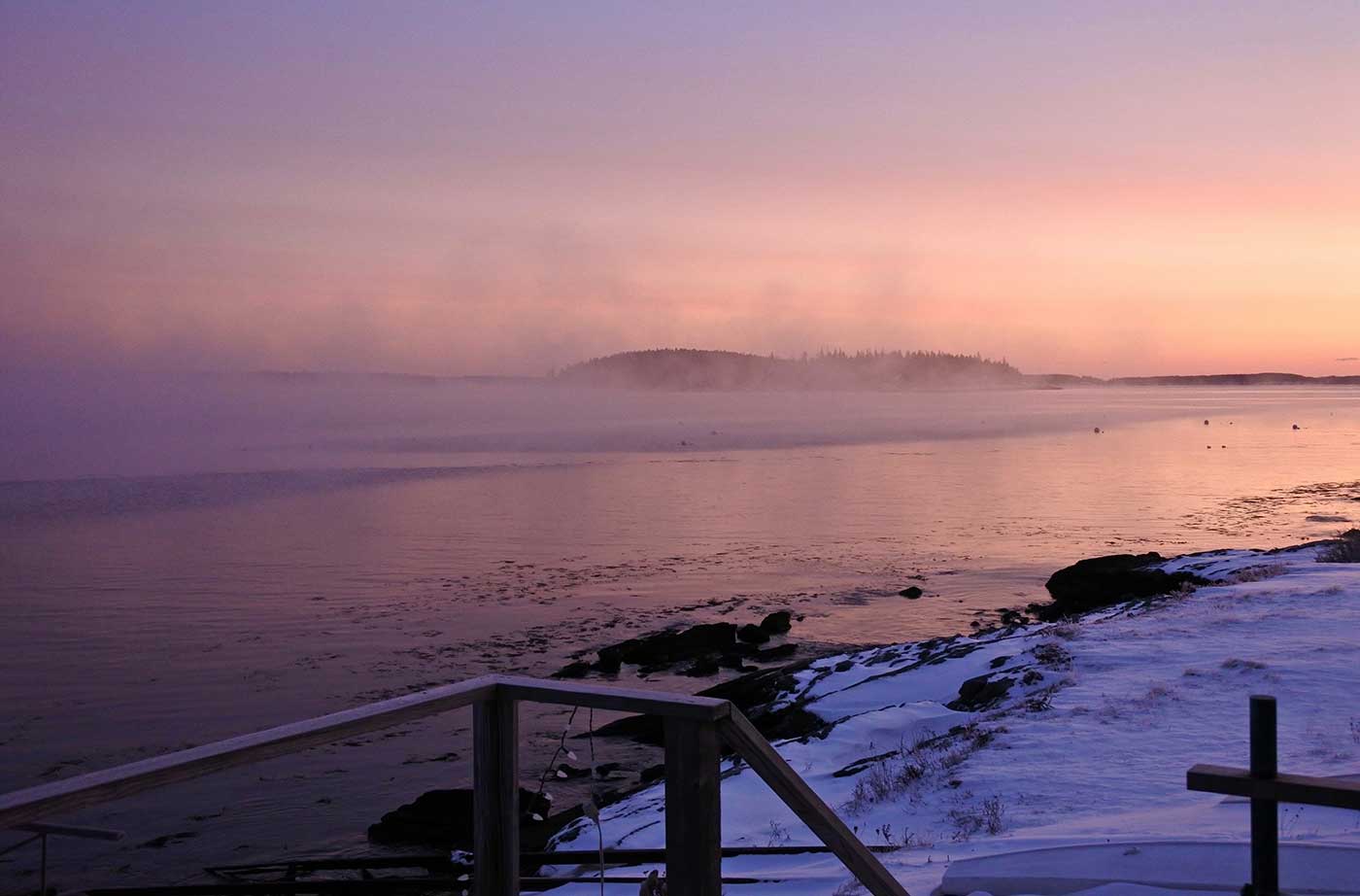 pink sky and sea smoke on ocean near shore