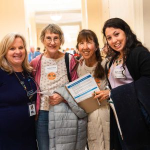 four women posing and smiling together at State House