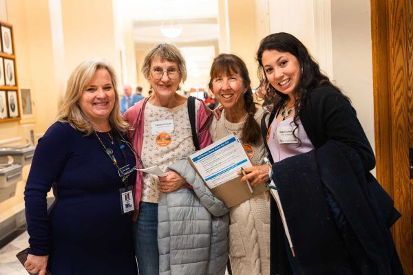 four women posing and smiling together at State House