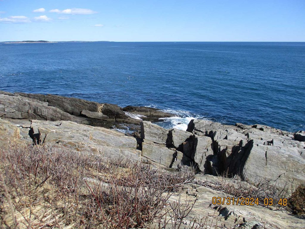 View of ocean and blue sky from rocky coastal trail
