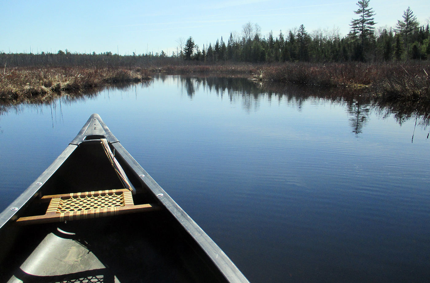 front of canoe headed down a calm waterway