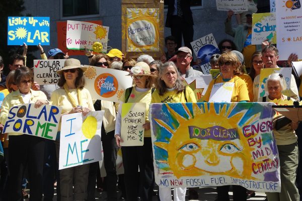crowd of people with signs in support of solar and other renewable energy