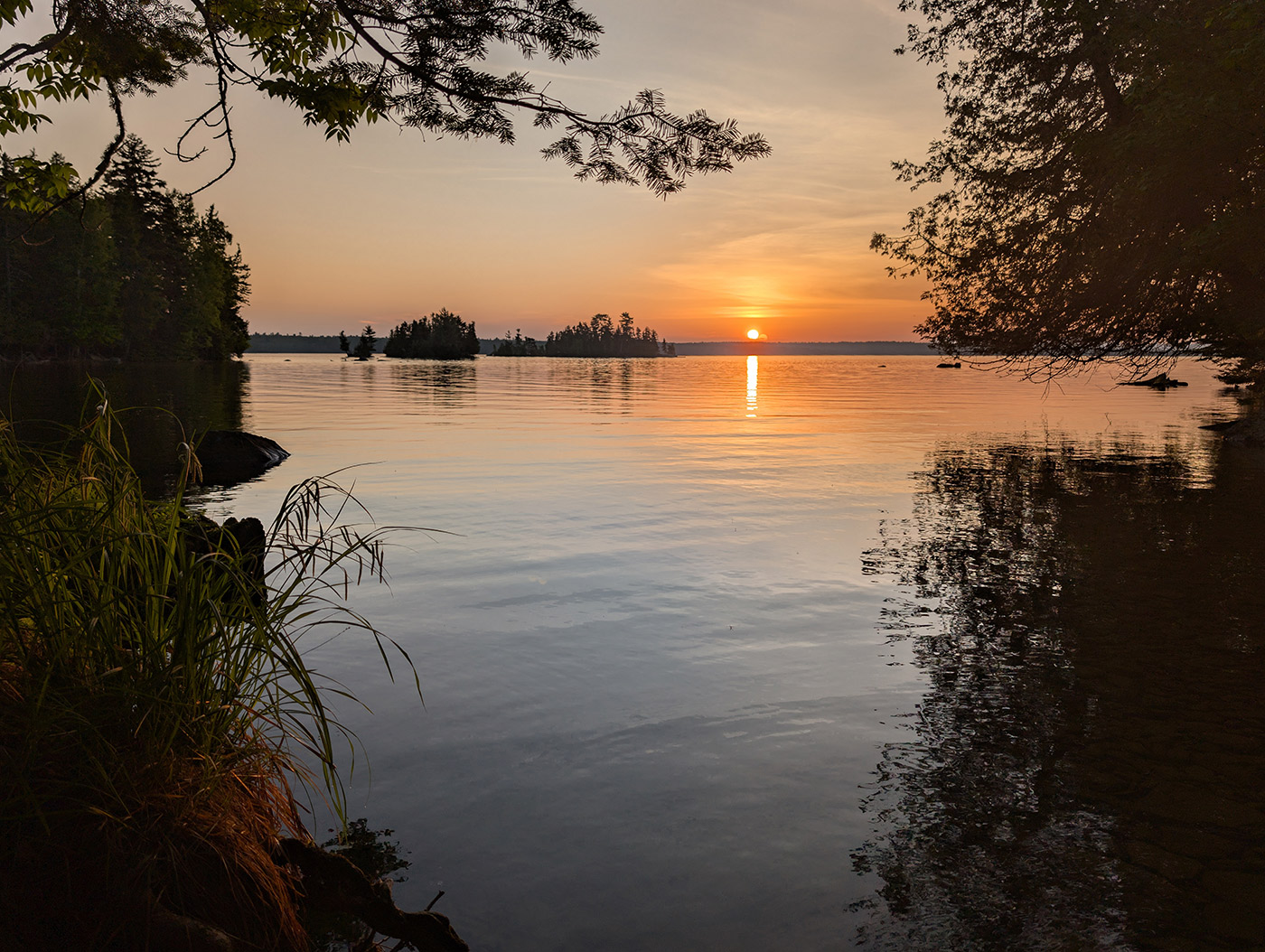 Sunset with sun at horizon as seen across a lake