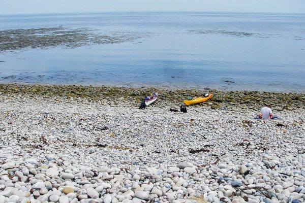 two kayaks on rocky beach next to ocean