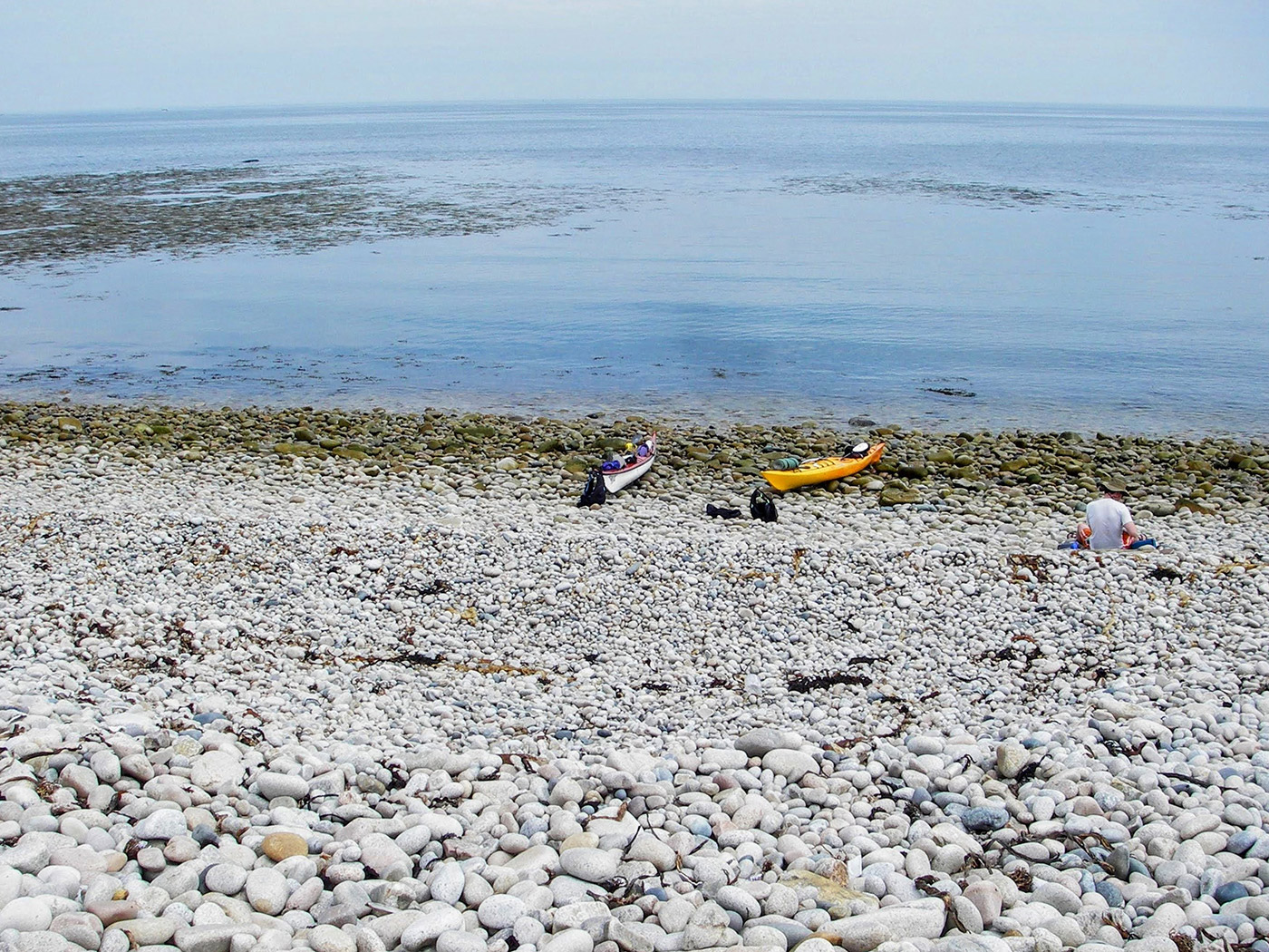 two kayaks on rocky beach next to ocean