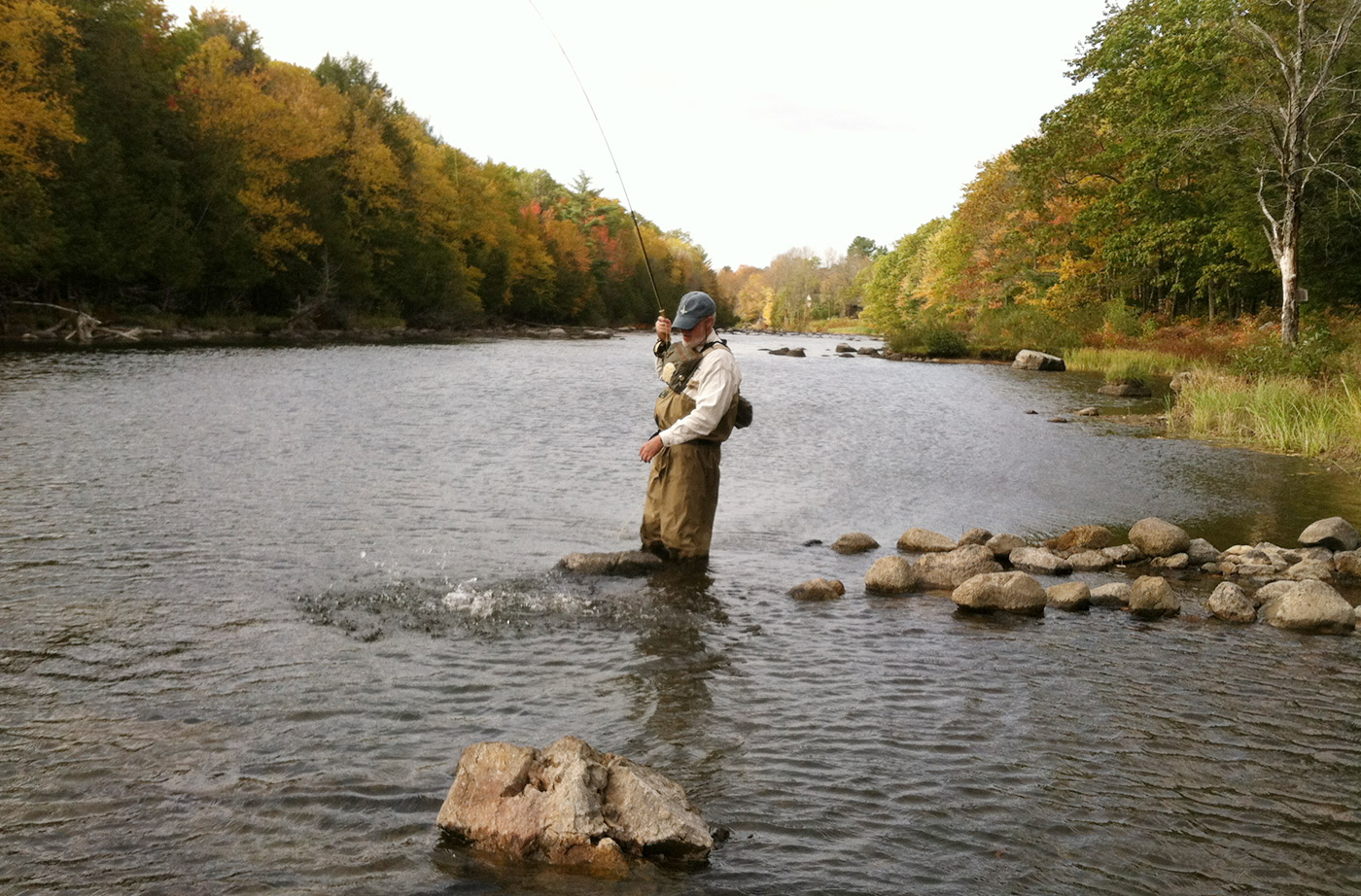 someone fishing for salmon wading in stream