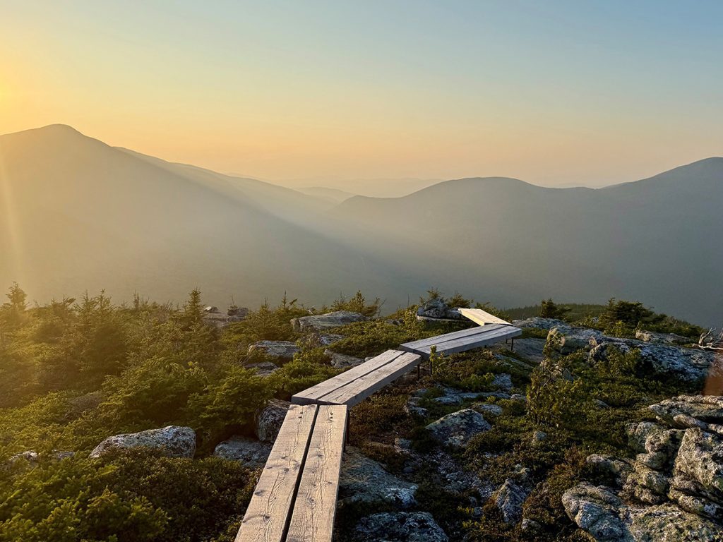 hazy sky over mountains, with wooden plank trail in foreground