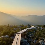 hazy sky over mountains, with wooden plank trail in foreground
