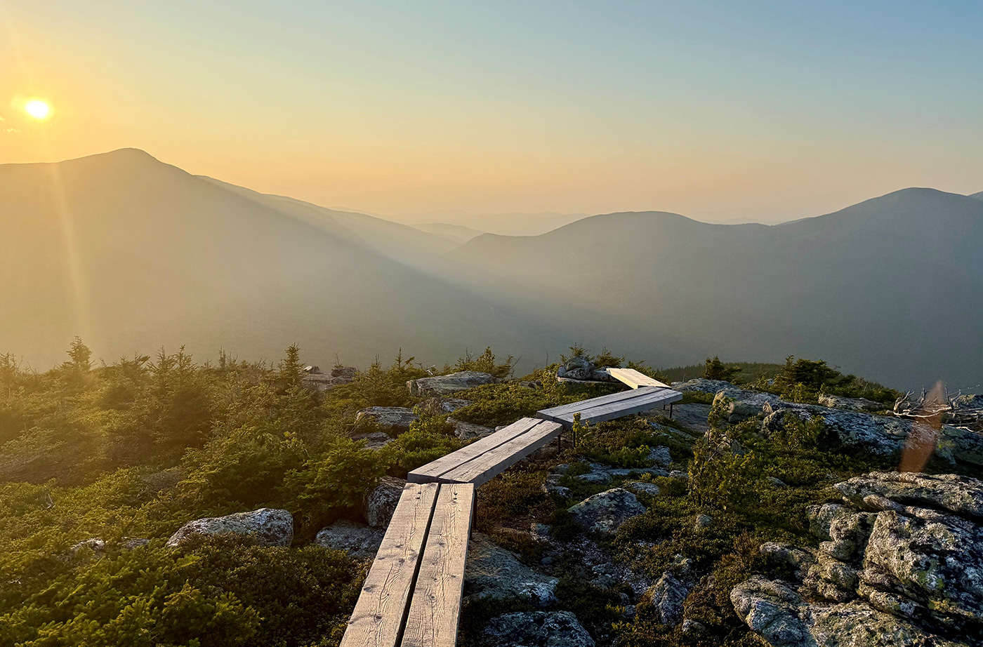 hazy sky over mountains, with wooden plank trail in foreground
