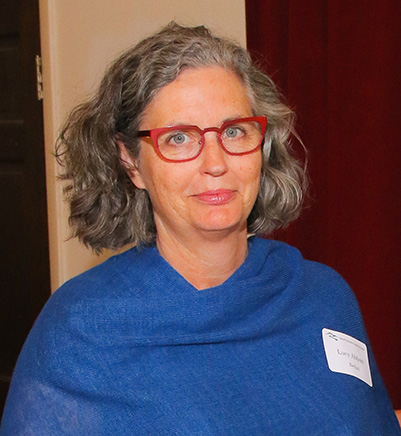Woman with red glasses and blue scarf smiling at camera