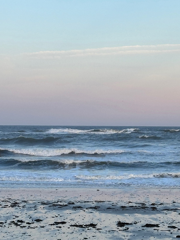 Pink sky and big ocean waves as seen from beach