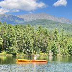 person paddling in yellow kayak with Katahdin in the background