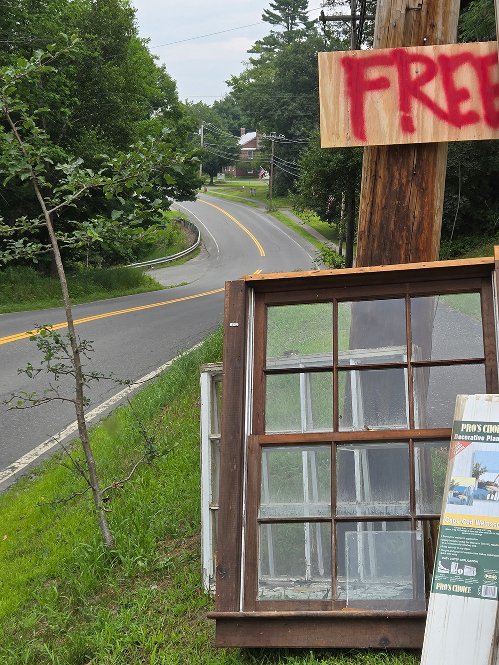 windows leaning against telephone pole next to paved road