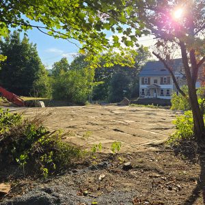 dirt-covered ground with yellow house in next lot behind it