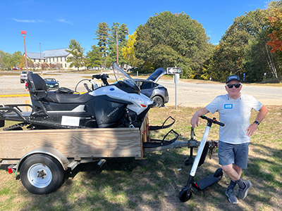 man standing next to trailer with snowmobile on it