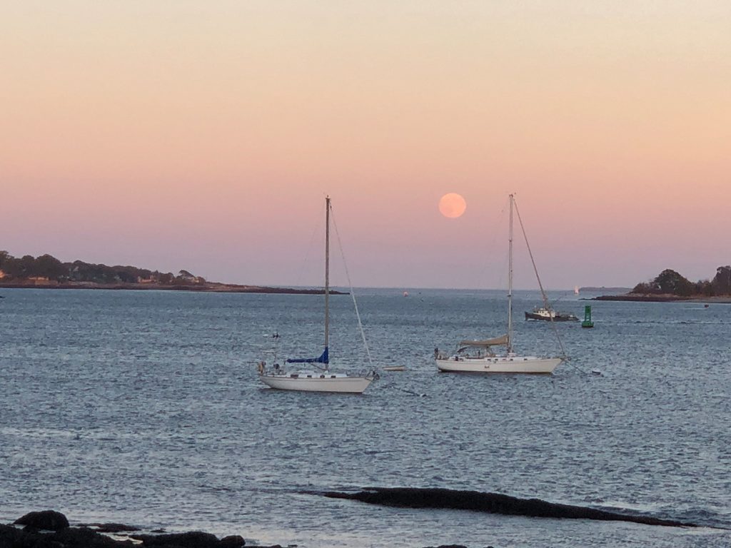 Moon and pink sky over Casco Bay with two boats in foreground