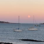 Moon and pink sky over Casco Bay with two boats in foreground